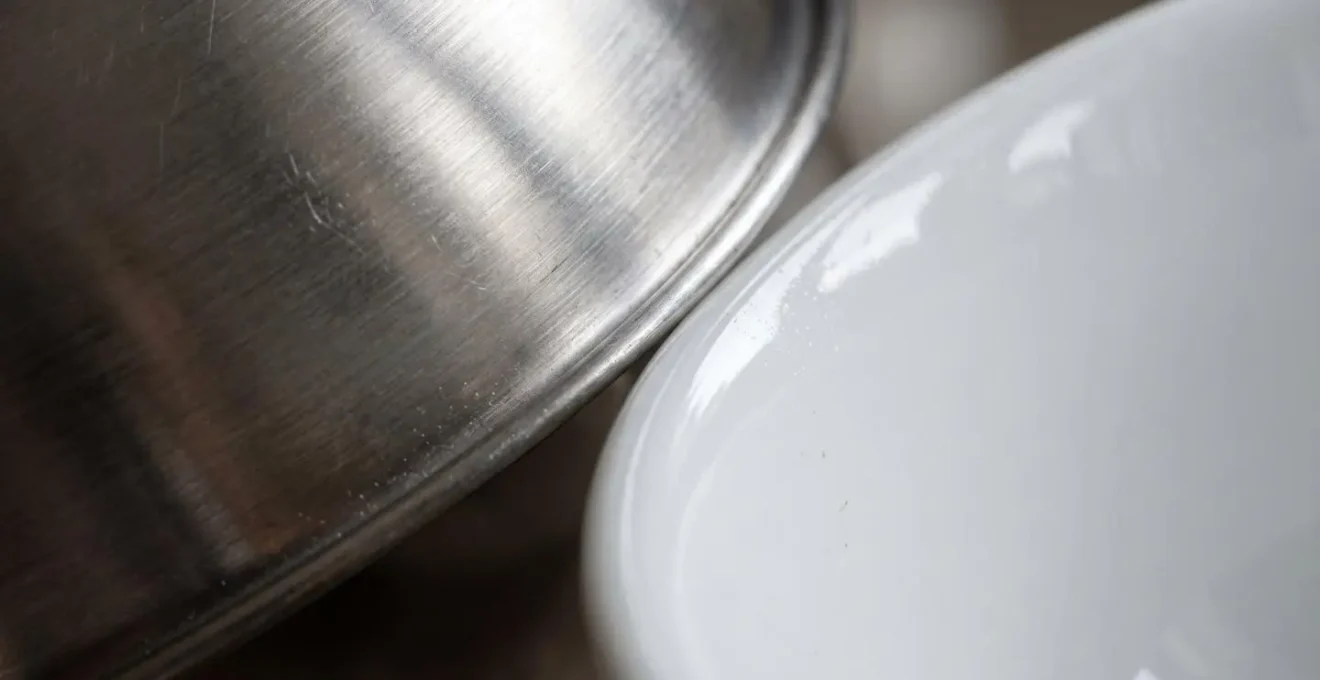 Détail macro des surfaces d'une gamelle en acier inoxydable et céramique montrant leur texture non poreuse